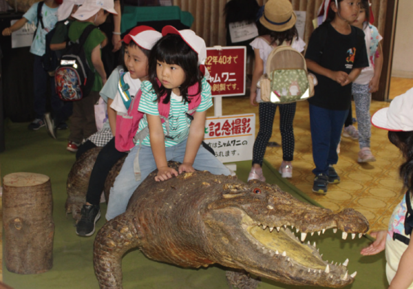 草津熱帯園でシャムワニ（剥製）に乗るこどもたち